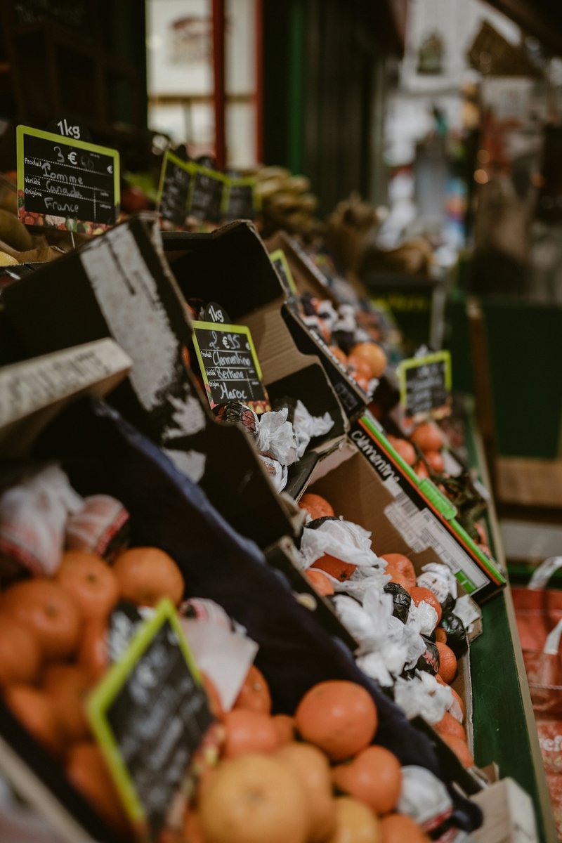 Étal de primeur parisien, cagettes de fruits et prix à la craie sur ardoises