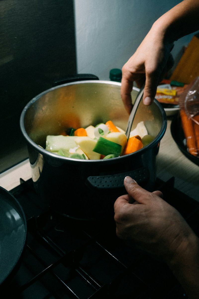 Mains préparant une marmite de légumes sur le feu